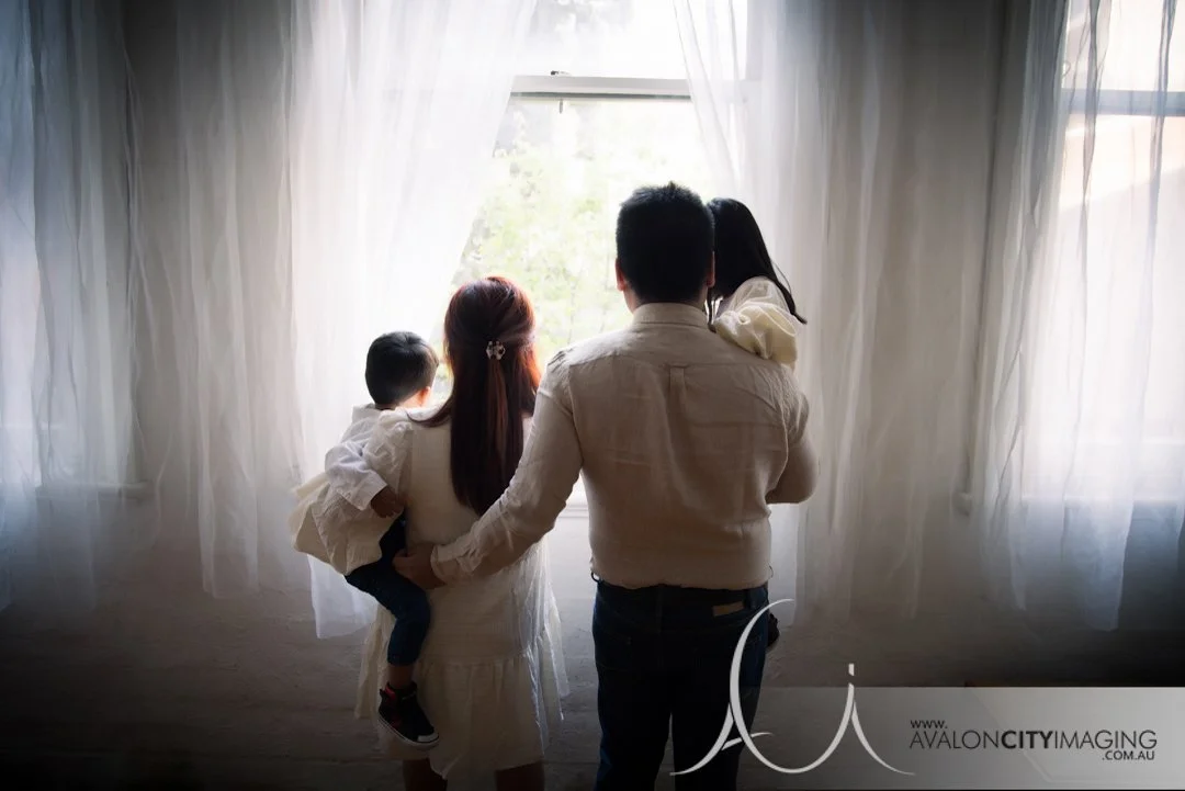 Family photography- parents and children looking out a studio window with natural lighting.jpg