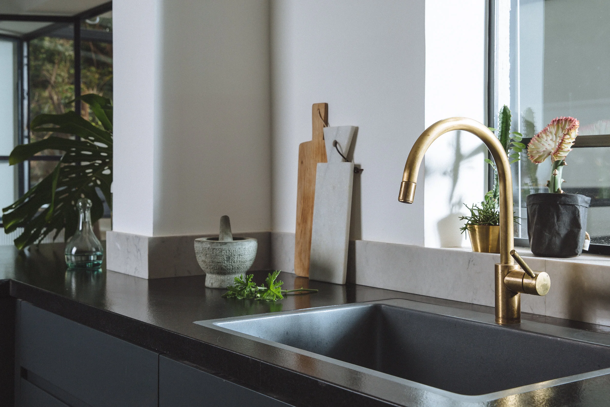 Dark themed kitchen, minimalist and elegant. Brass faucet
