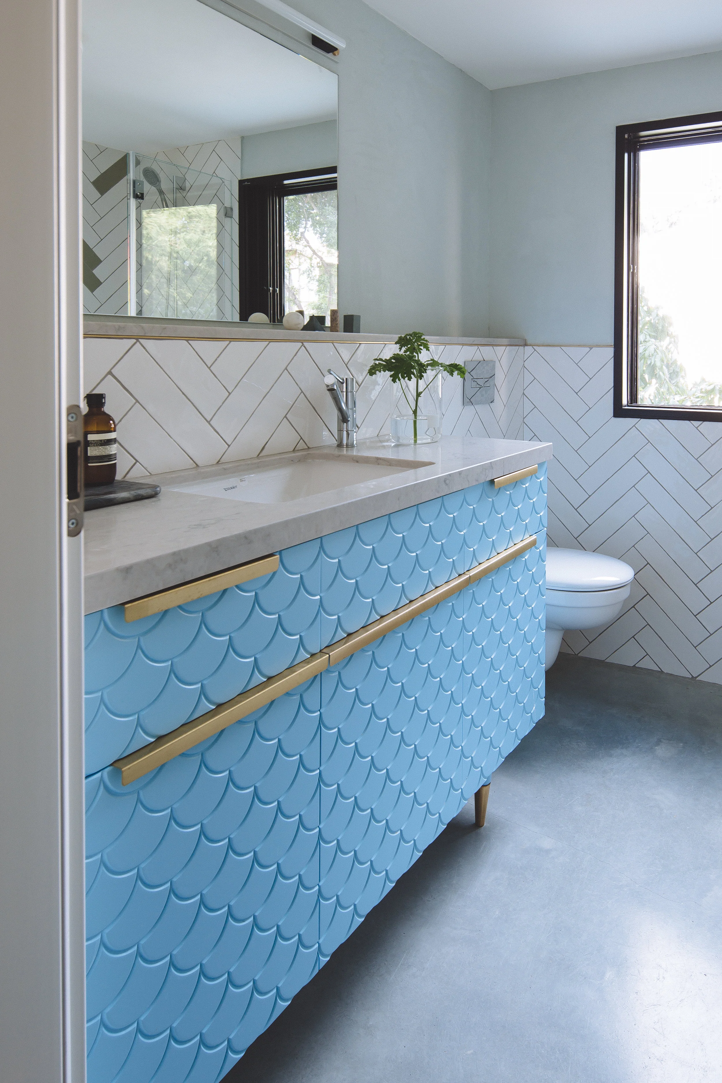 Blue bathroom cabinet. Concrete floor and brass details