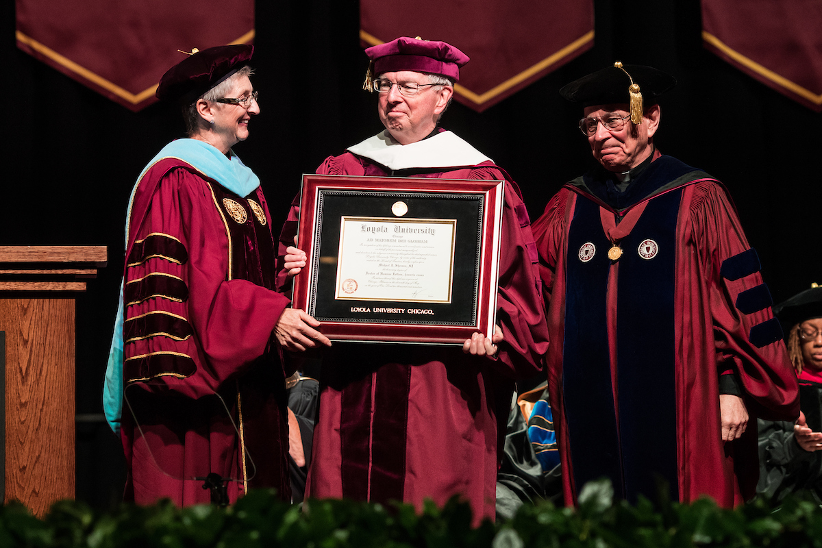 Rev. Michael J. Sheeran, S.J. receives his honorary degree from Jo Ann Rooney, JD, LLM, Ed.D., president of Loyola University Chicago, and Rev. Thomas J. Regan, S.J., Dean of the Graduate School and the College of Arts and Sciences at Loyola (photo by Lukas Keapproth)