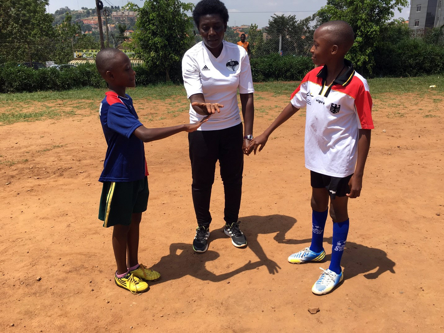 Majidah Nantanda conducting the pre-game coin toss with players wearing jerseys and gear donated by clubs in the US.