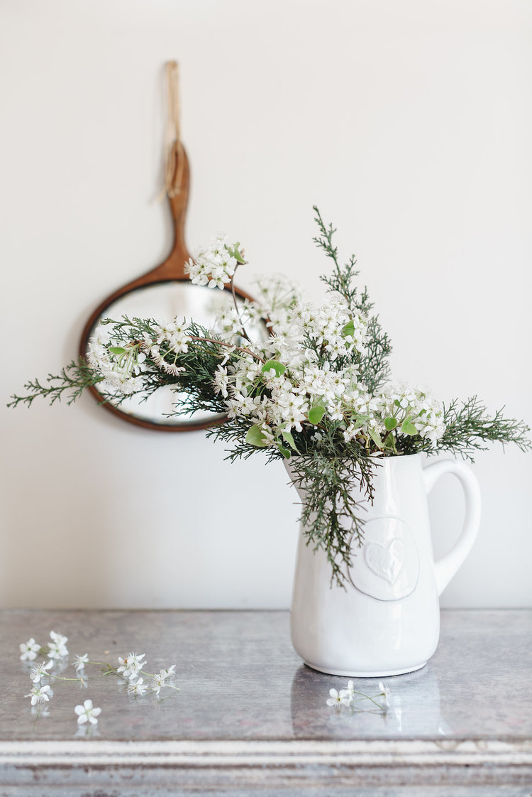 A farmhouse white pitcher and vintage mirror a few of the accessories in the bridal suite at the McConnell House designed by Kim Leggett, owner of City Farmhouse