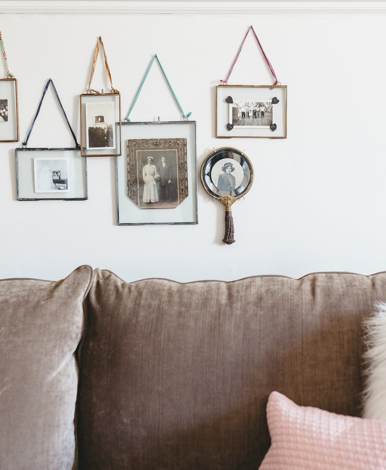 Layered picture frames filled with antique pictures are hung behind the cozy sofa in the bridal suite at the McConnell house | Interior Design: Kim Leggett, owner of City Farmhouse