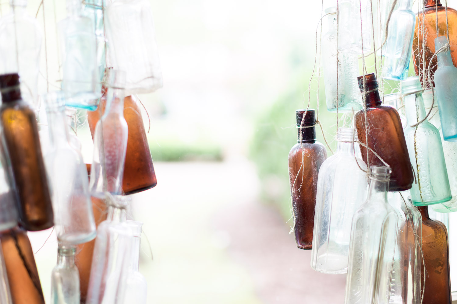 Vintage glass bottles hang from twine at Homestead Manor | Interior Design: Kim Leggett | Photographer: Alyssa Rosenheck