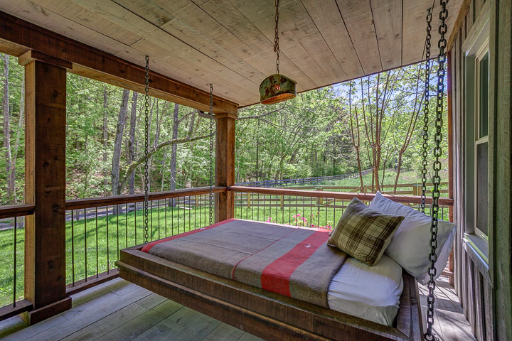 A porch bed hangs from the ceiling outside at the Nest | Interior Designer: Kim Leggett