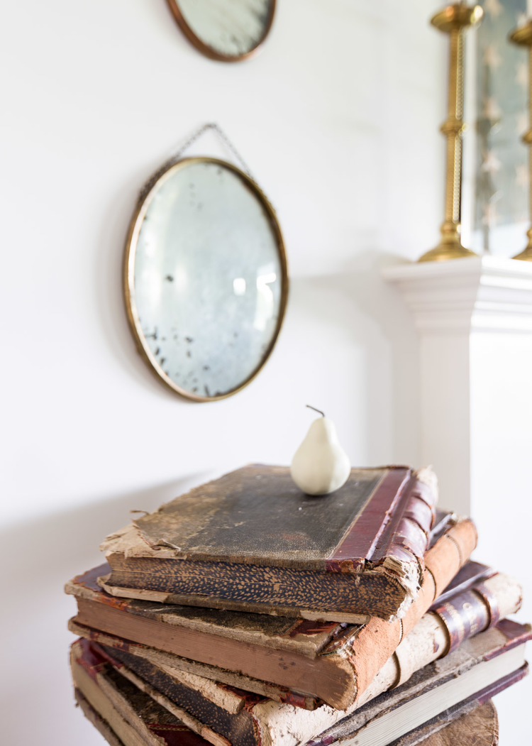 A vintage round mirror and antique book accent the space at One King's Lane | Photography: Alyssa Rosenheck | Interior Design: Kim Leggett