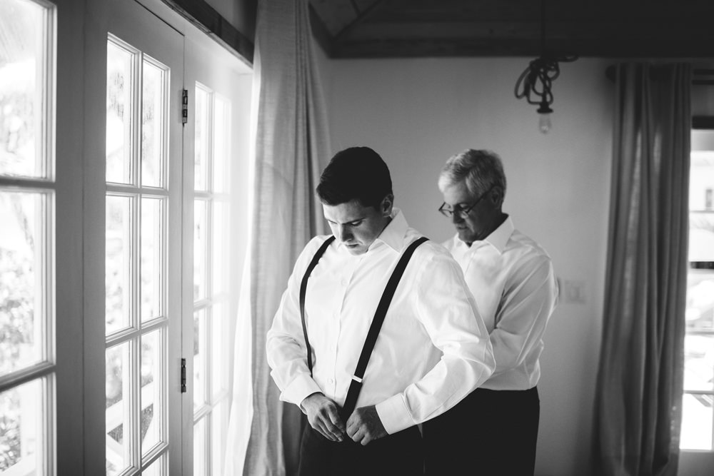 ocean view club wedding : groom putting on suspenders