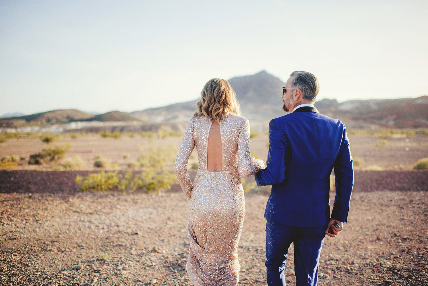 neon museum wedding - bride and groom walking thru desert