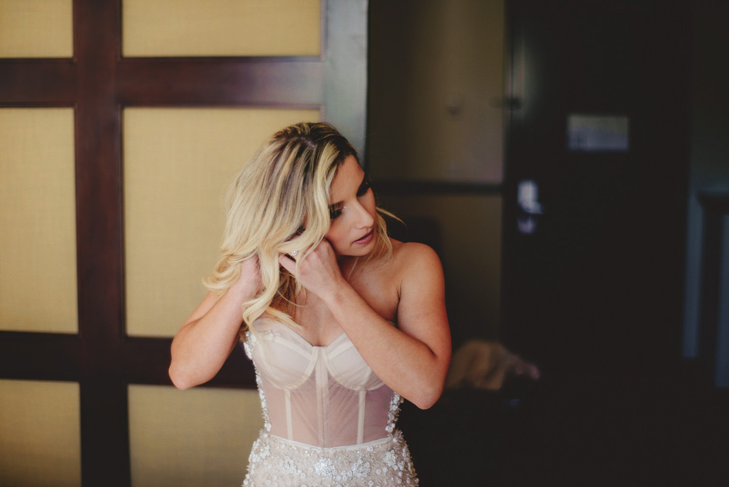 editorial ringling wedding: bride putting in ear rings
