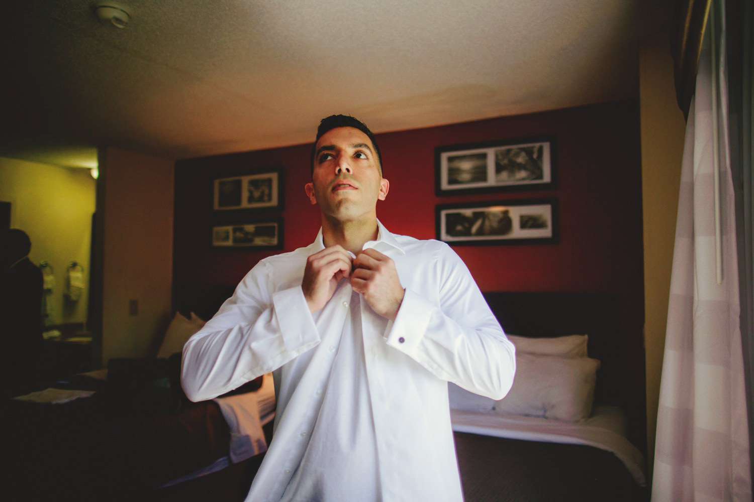 editorial ringling wedding: groom putting on shirt