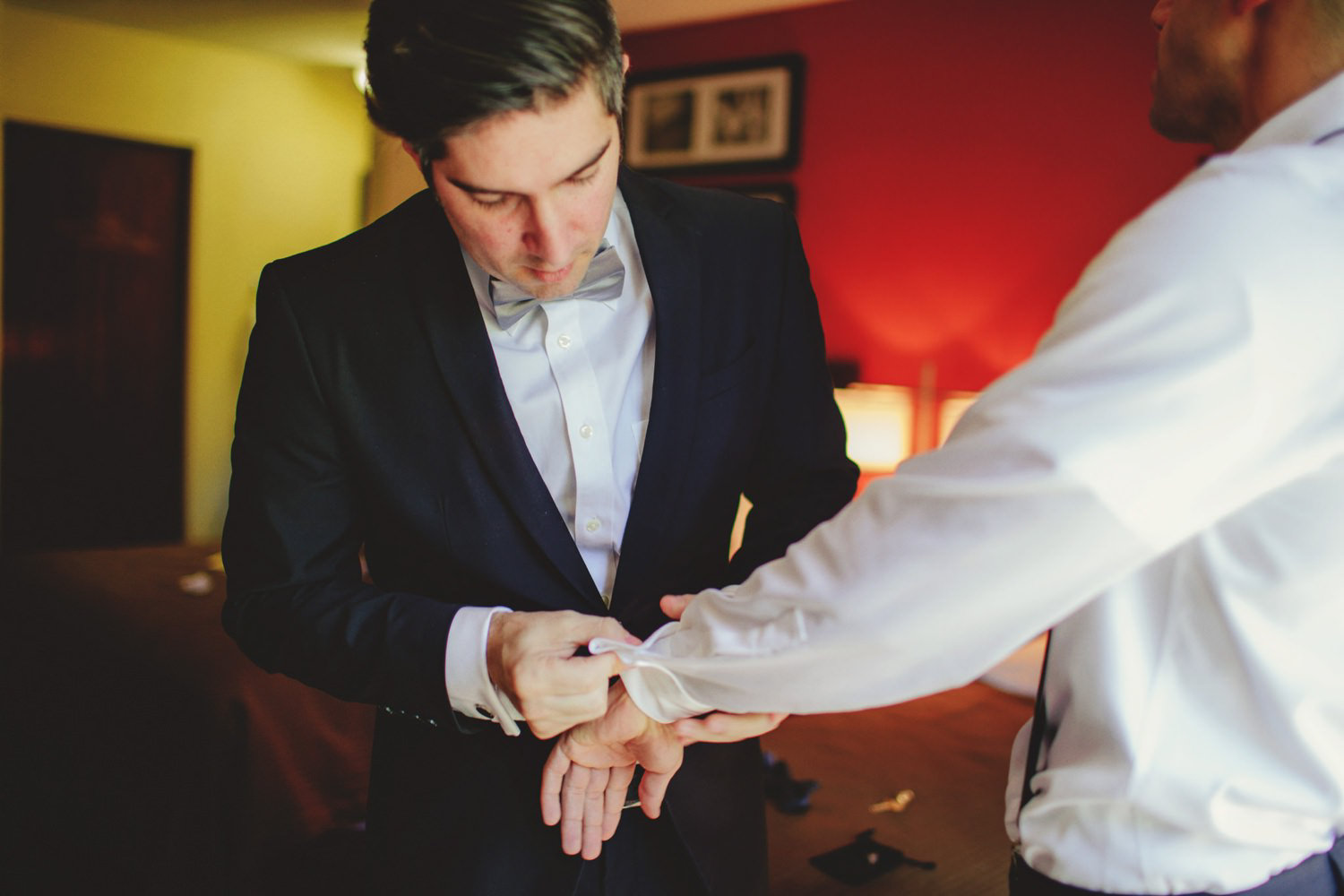 editorial ringling wedding: best man helping with cufflinks