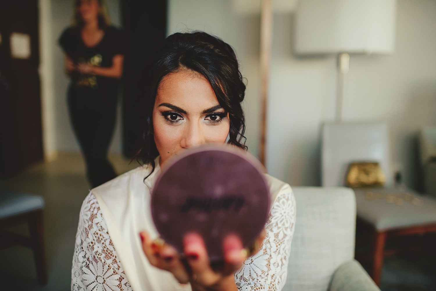 bride looking into makeup mirror