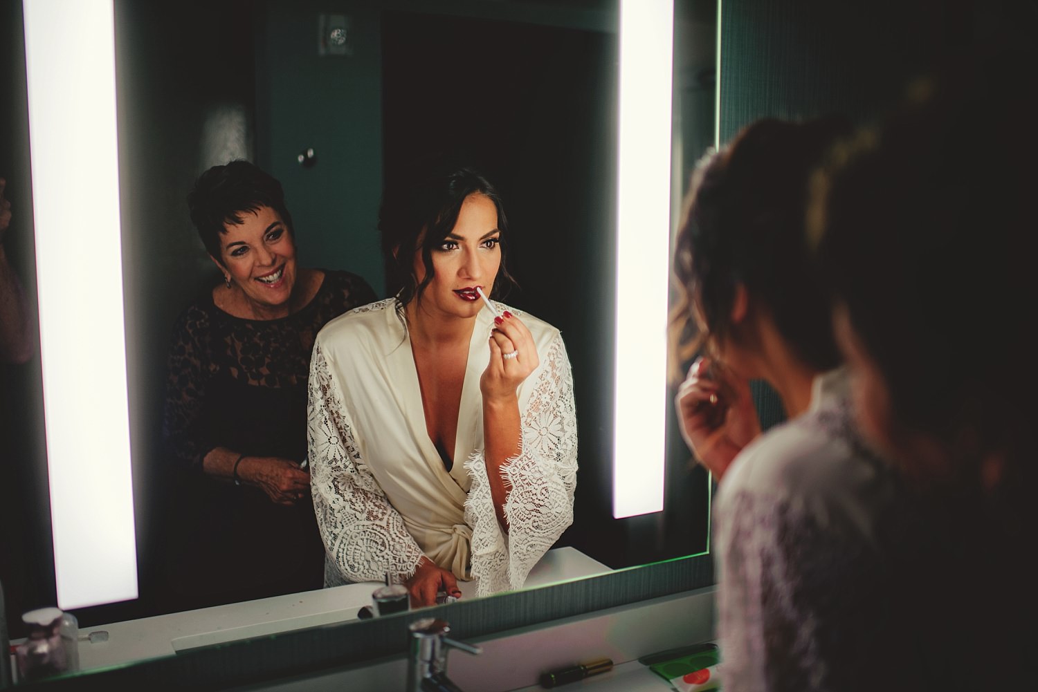 bride putting on lipstick in mirror