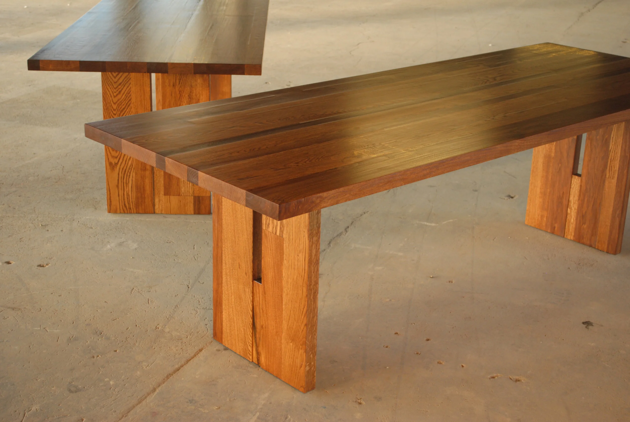 Set of custom oak and butternut dining tables with aluminum bar inlay and trestle legs.