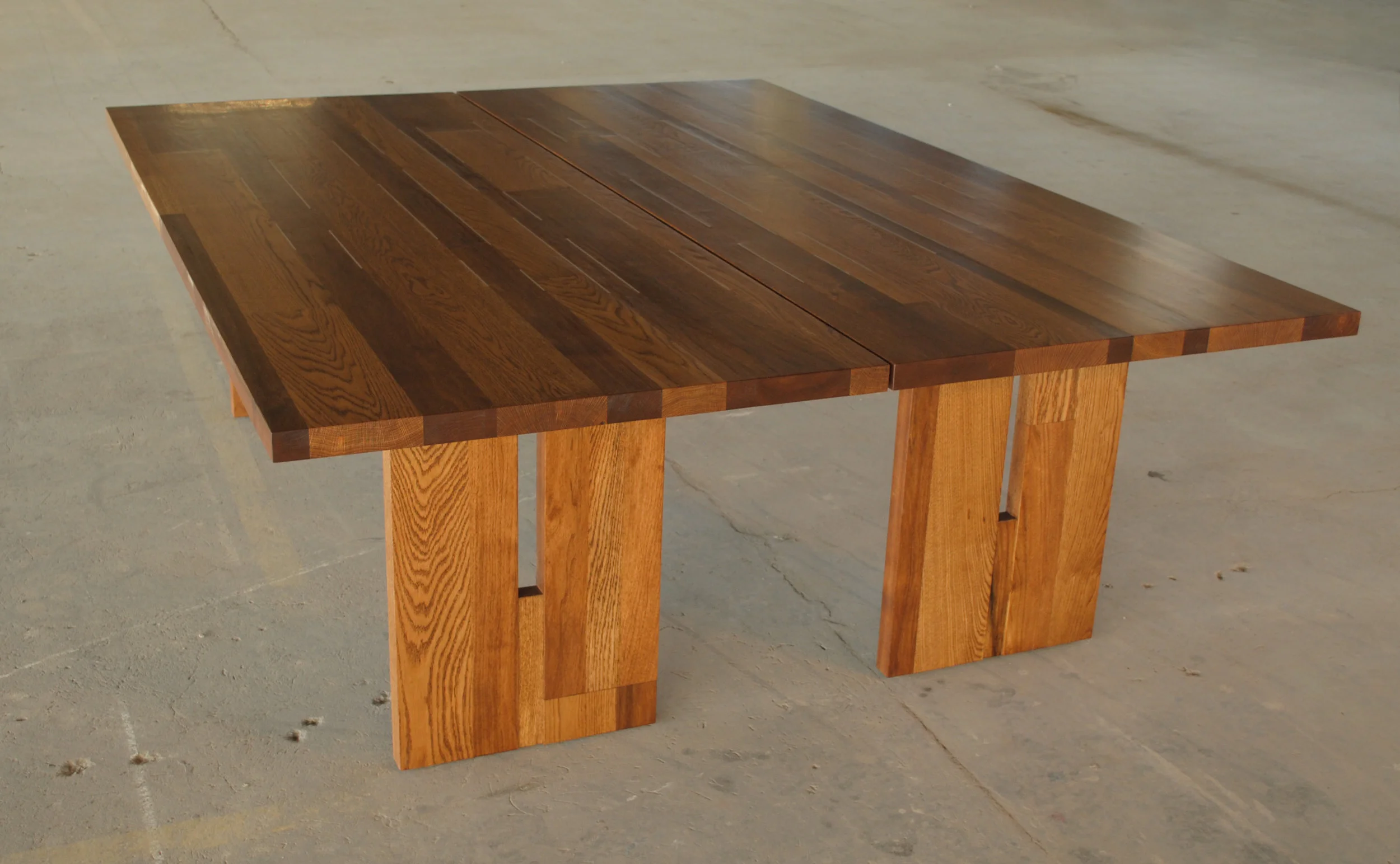 Set of custom oak and butternut dining tables with aluminum bar inlay and trestle legs.