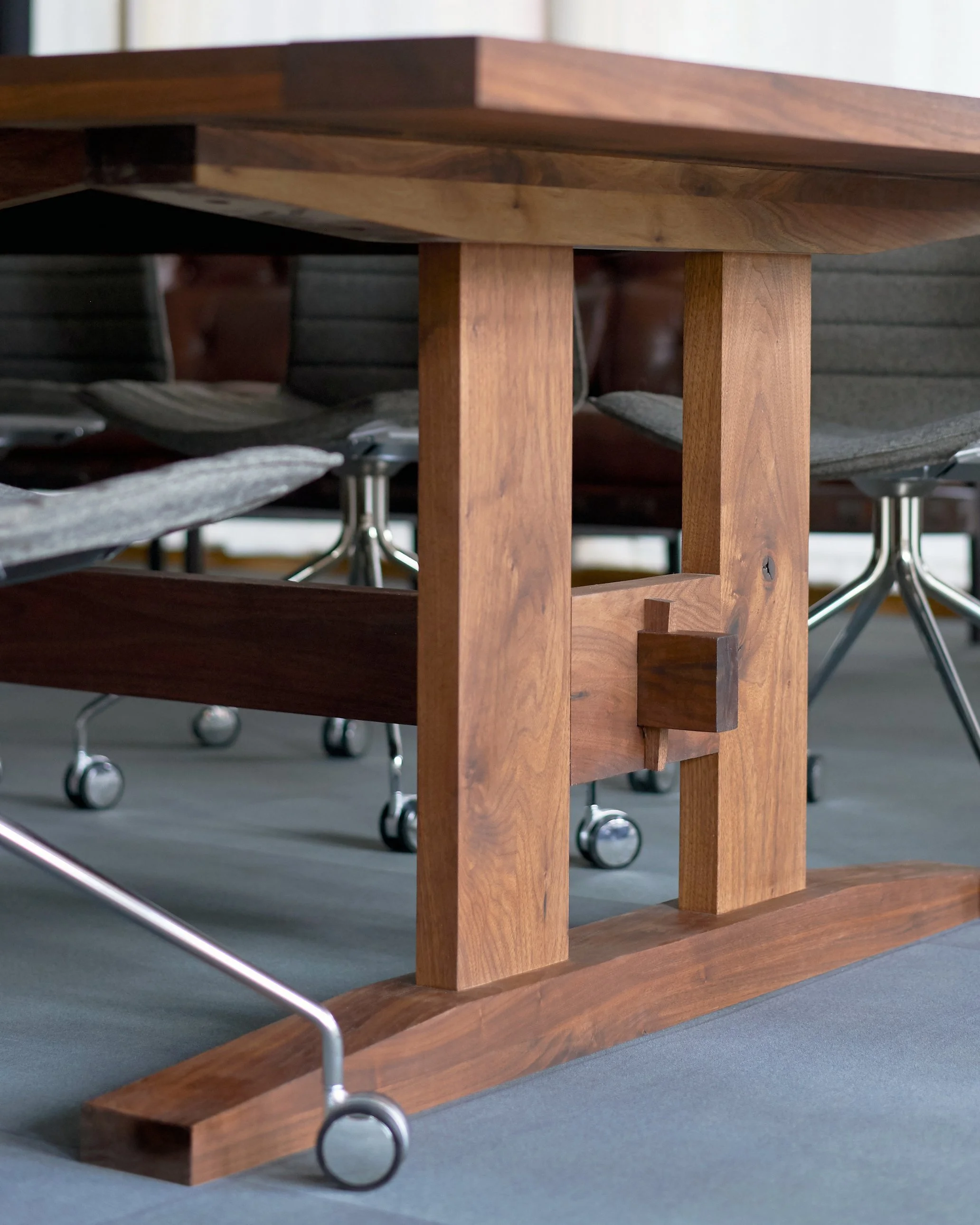 Walnut conference table with trestle base, wedged through tenon detail.