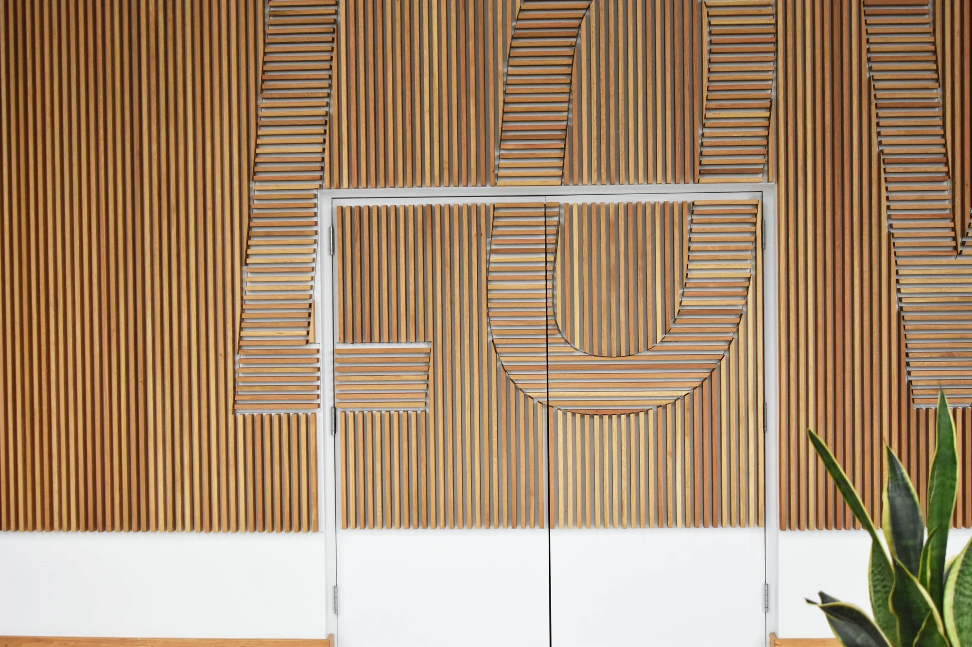 Typographic white oak slat wall installation door detail.