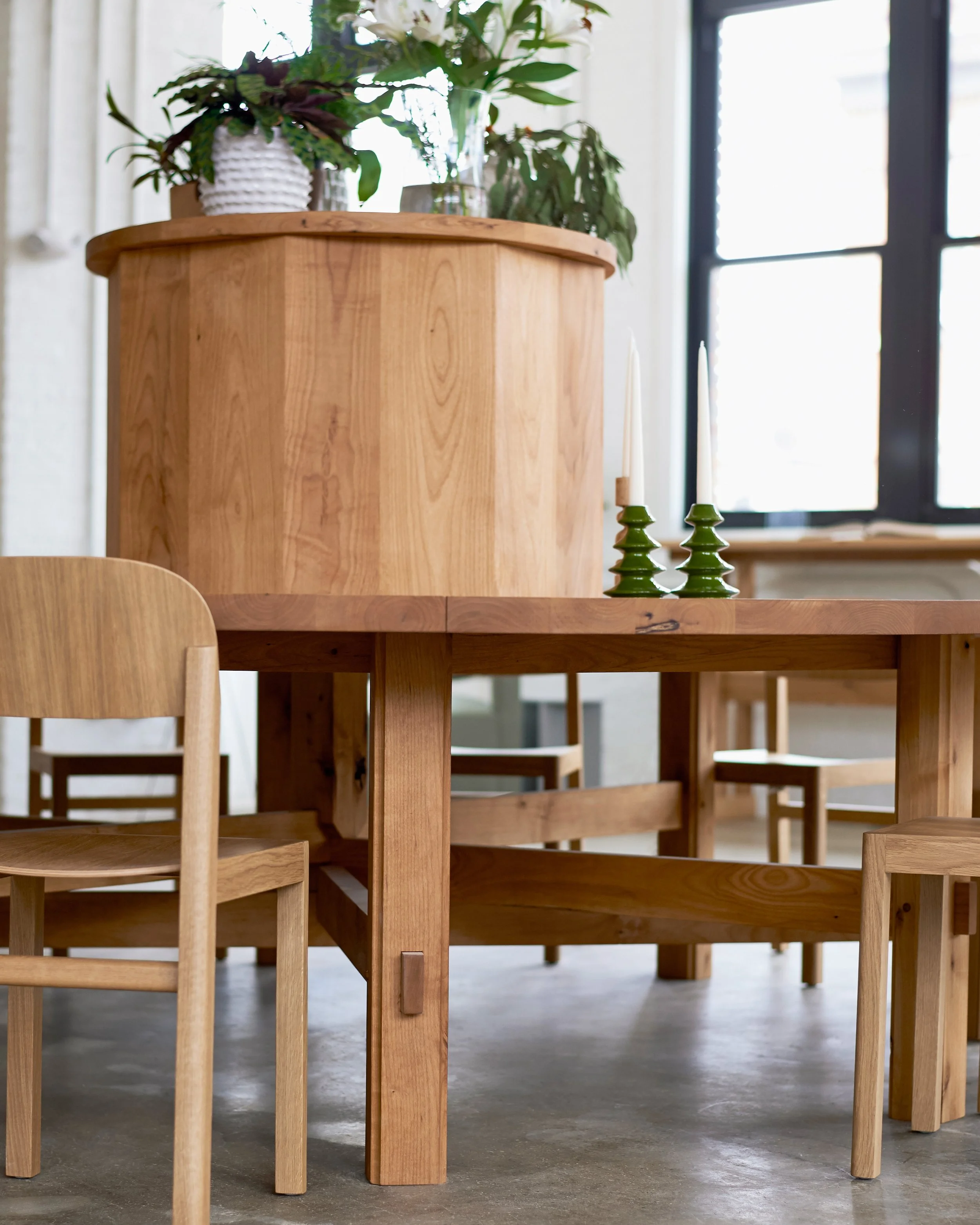 Custom designed 10' round alder common table with lap joint wheel base and through tenons; faceted alder riser platform.