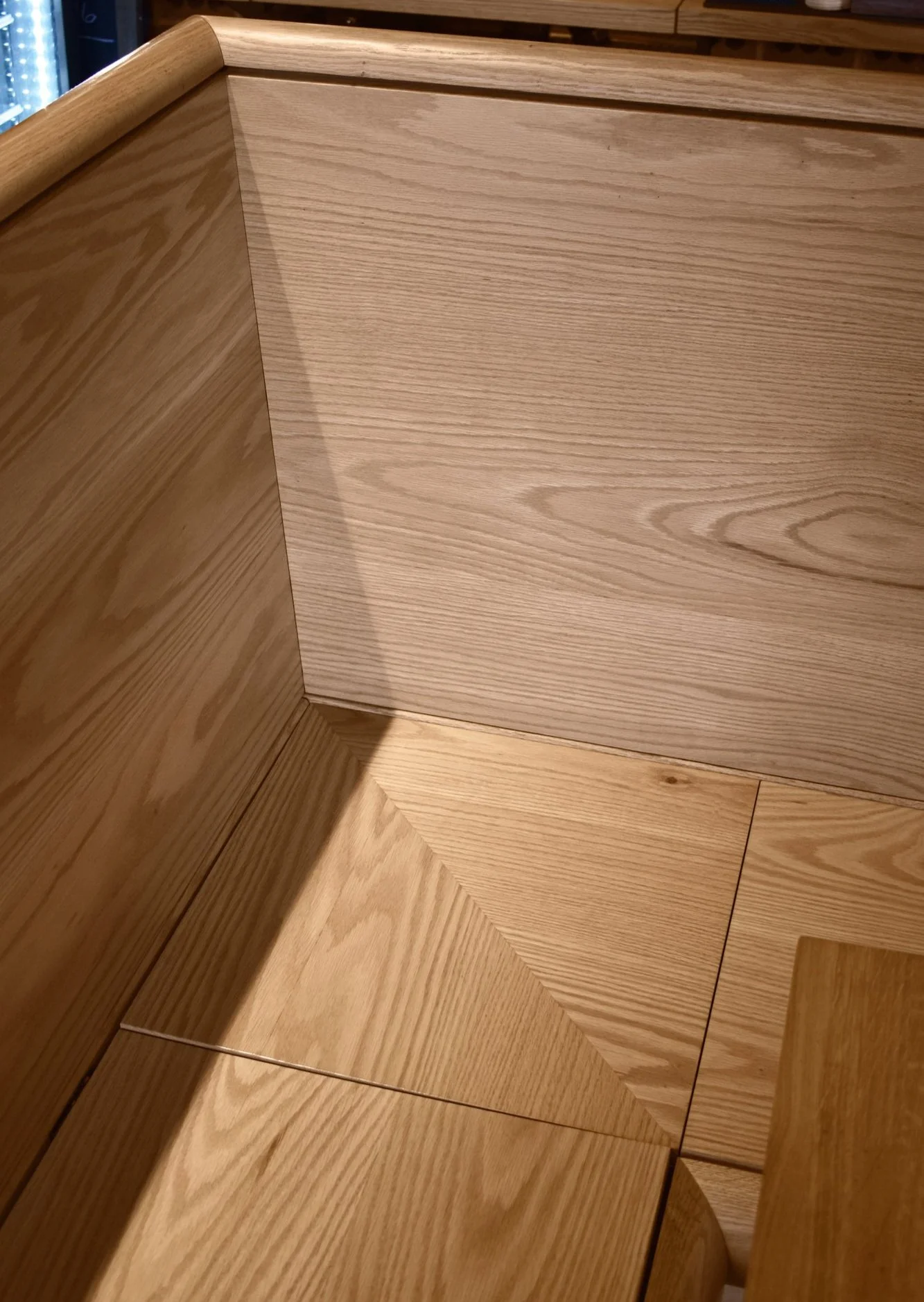 Custom red oak banquette seating with integrated storage, seat detail.