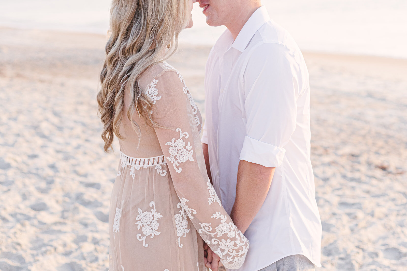  couple holding hands on beach for engagement photos 