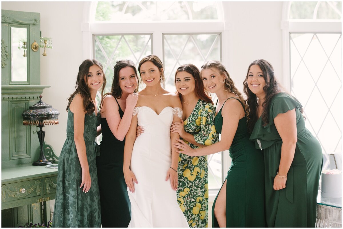  Bride with bridesmaids in green and yellow dresses during private estate wedding 