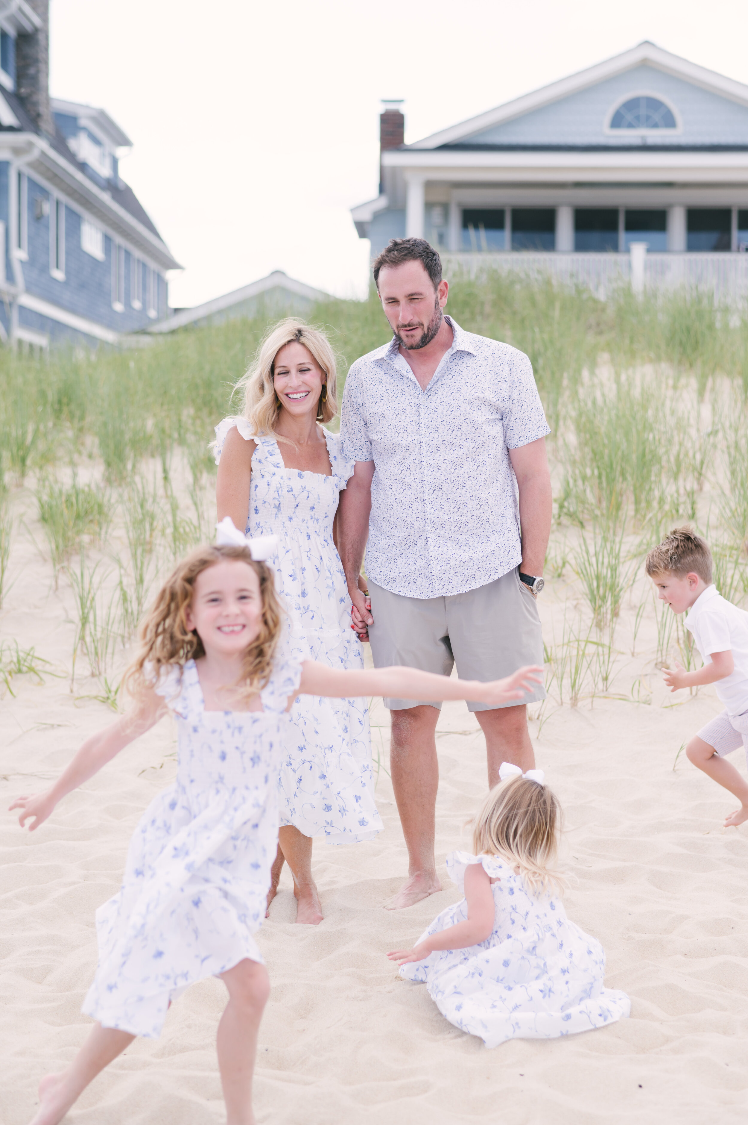 Kids playing during family photos on beach while parents look on  | NKB Photo