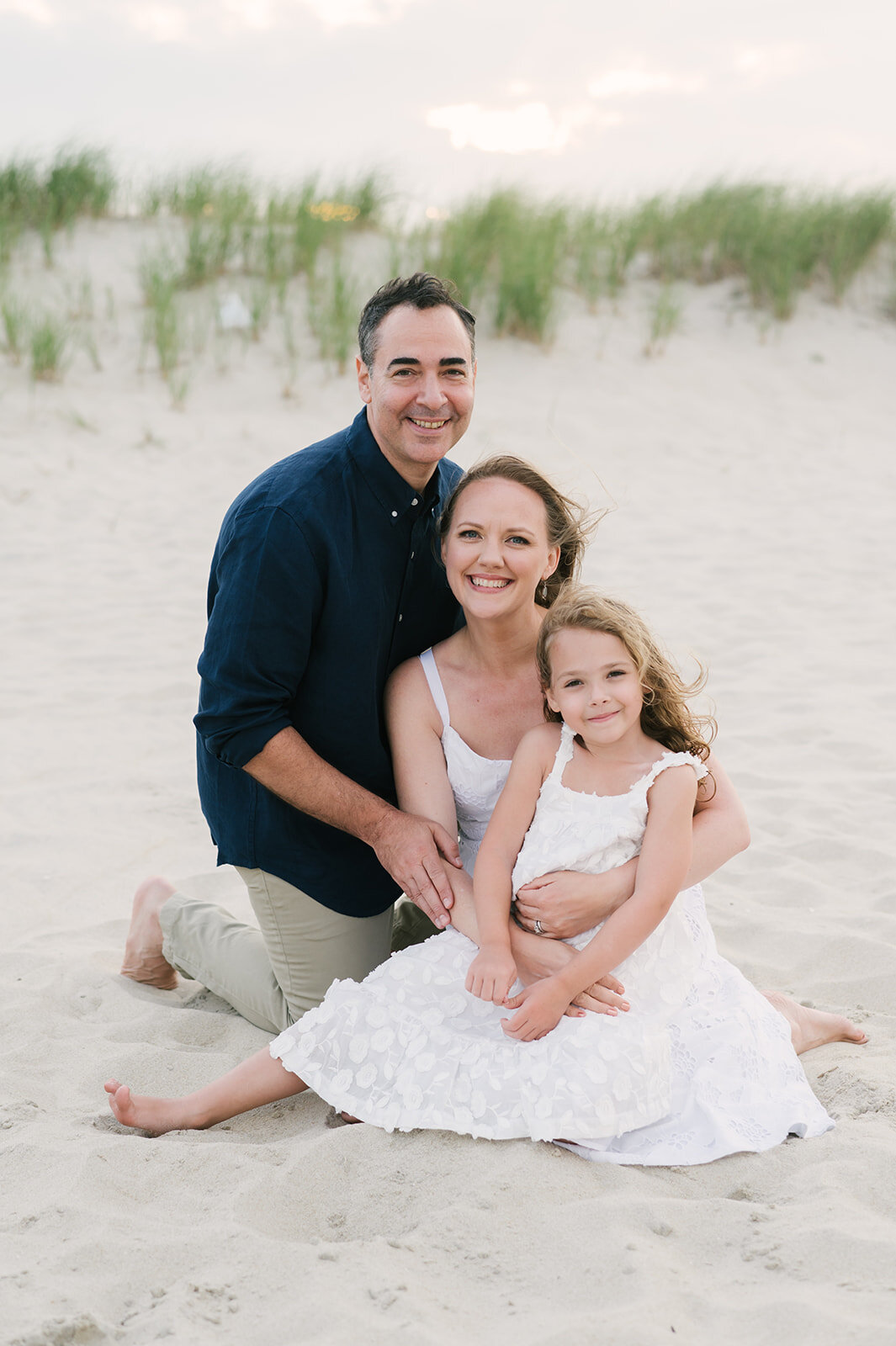 Mom, dad, and daughter posing on beach during family photos  | NKB Photo