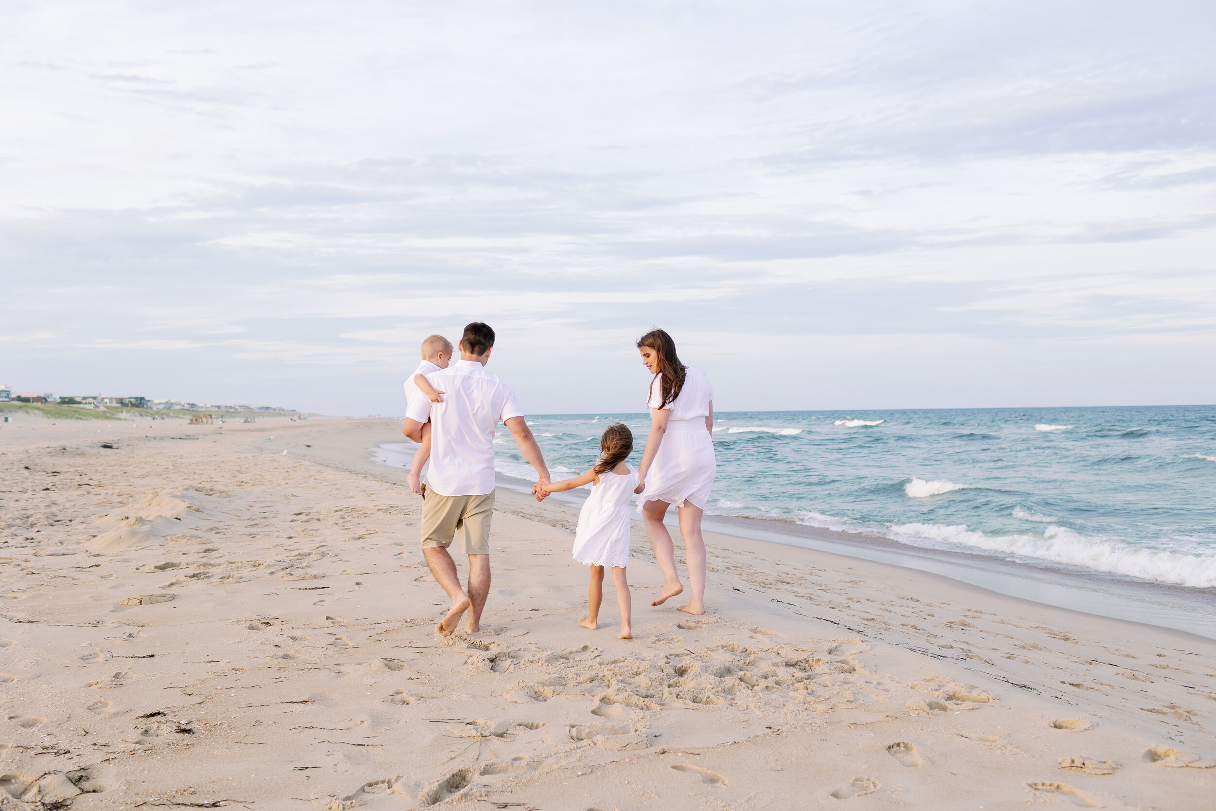 Beach photo ideas: family walking along beach and holding hands during family photos | NKB Photo