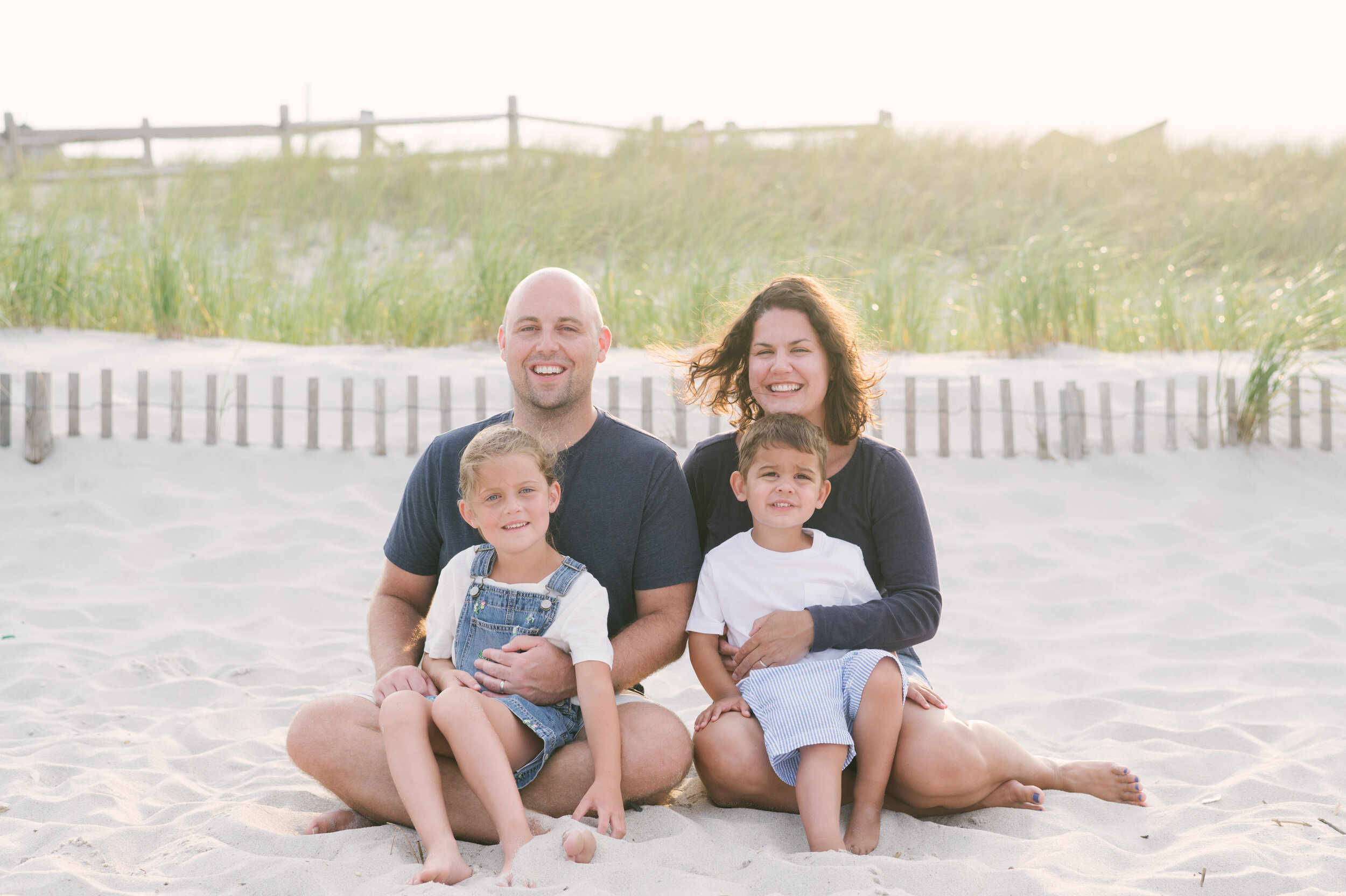 Beach photo ideas: Mom, dad, and two sons sitting on beach during photos  | NKB Photo