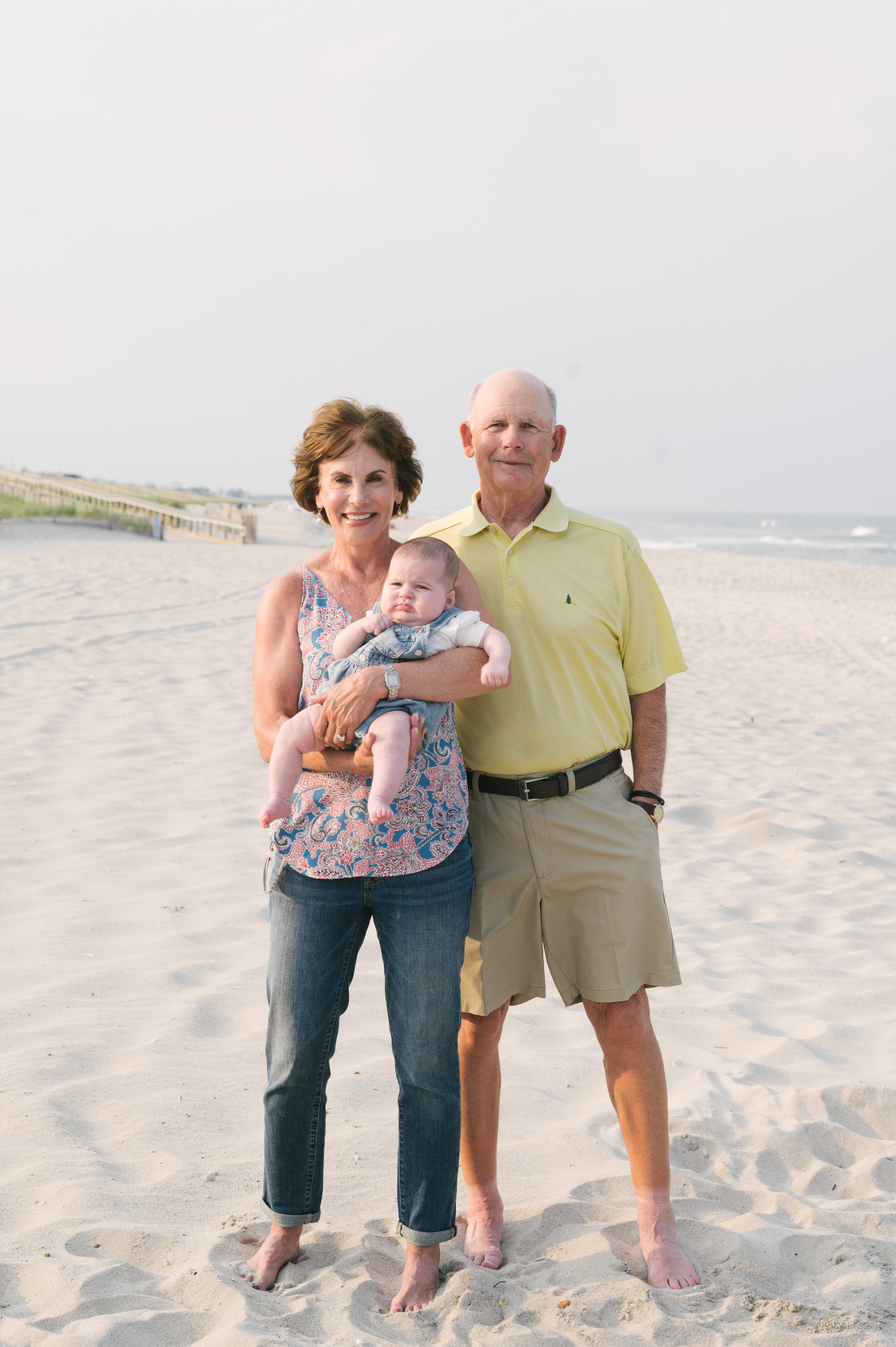 Beach photo ideas: Grandparents holding baby on beach during family beach photos | NKB Photo