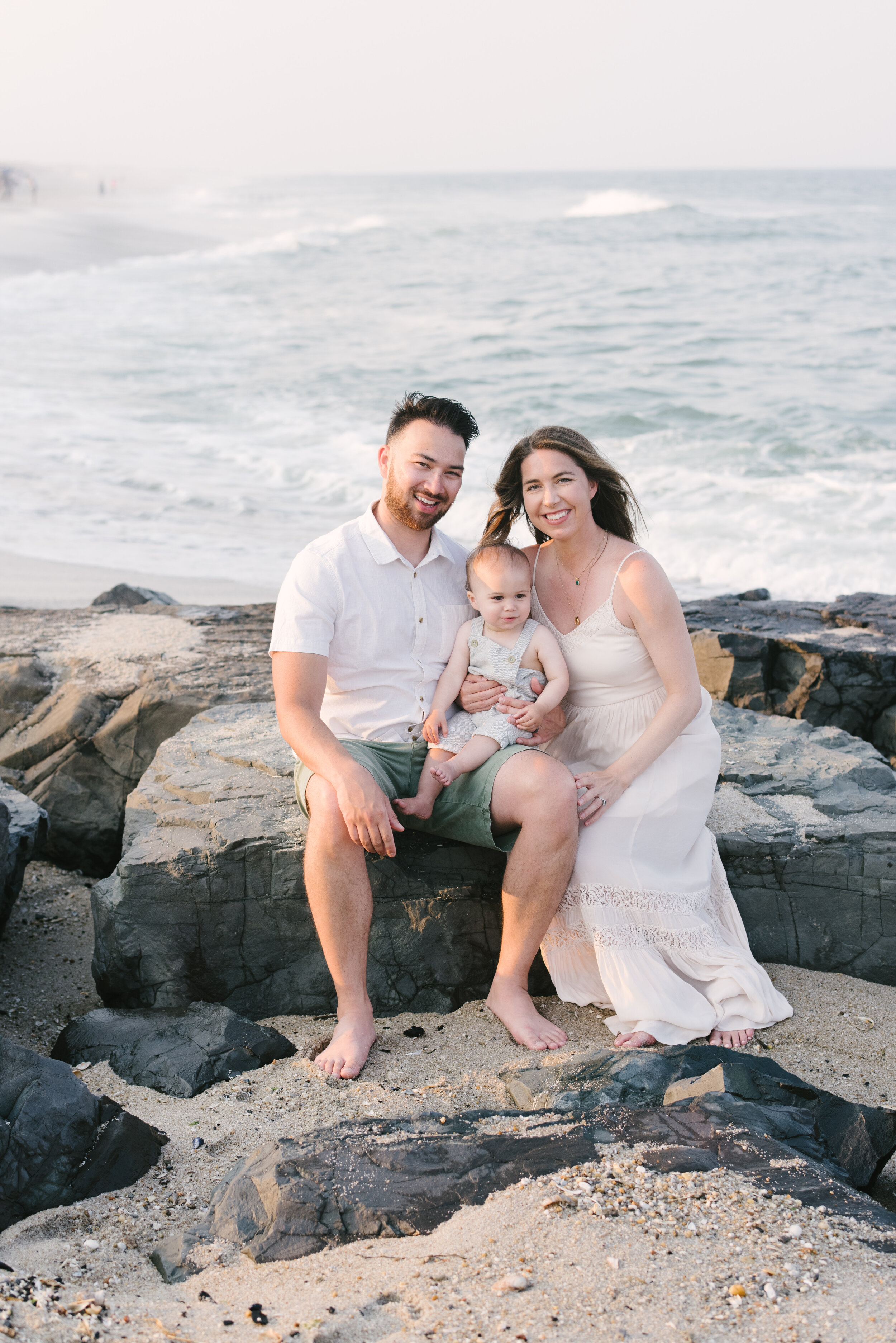 Mom, dad, and baby sitting on rocks during family photos  | NKB Photo