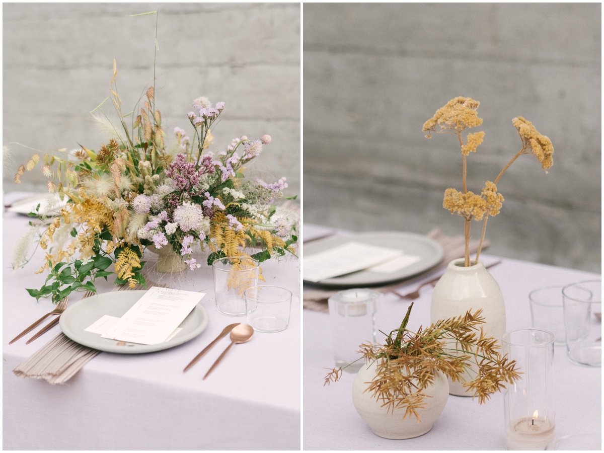 Muted purple and yellow floral arrangements on head table with purple table cloth and rose gold utensils | NKB Photo