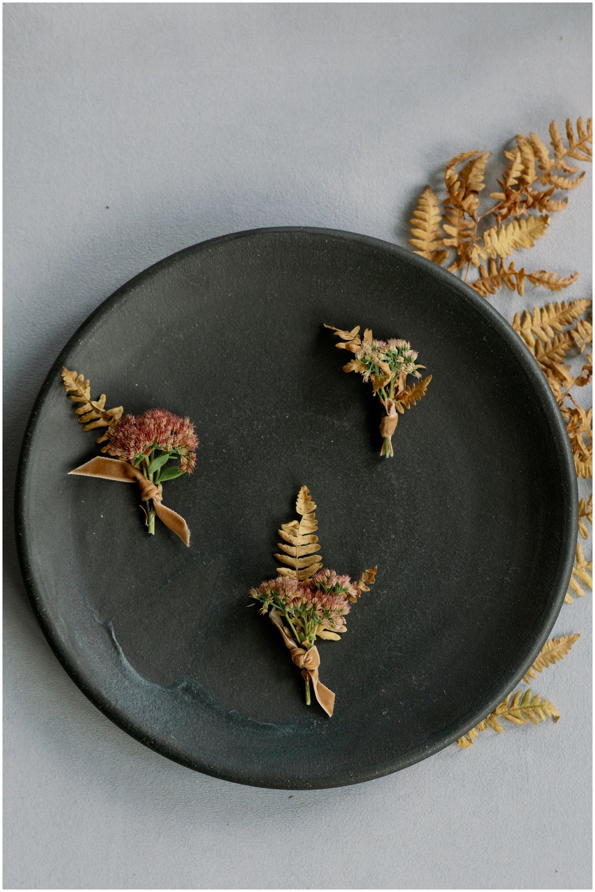 Pink and gold floral boutonnières laying on black plate during styled shoot | NKB Photo