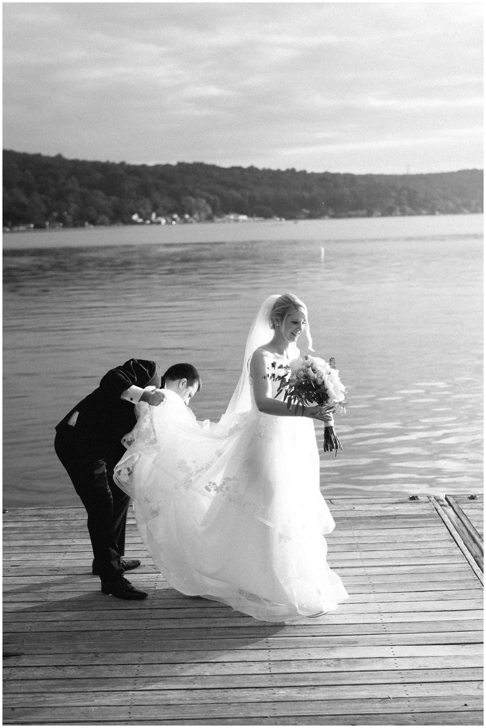 Groom picking up bride's dress on boardwalk at Lake Mohawk Country Club Wedding | NKB Photo