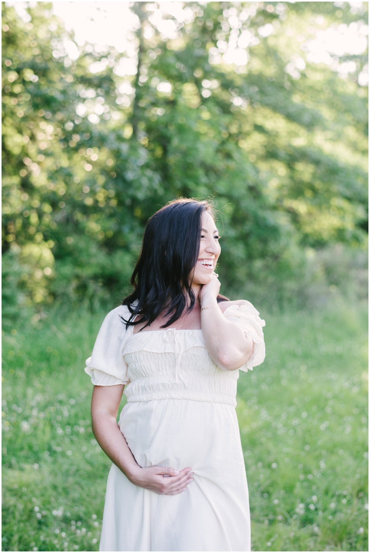 Woman looking off into distance and cradling baby bump during maternity session | NKB Photo
