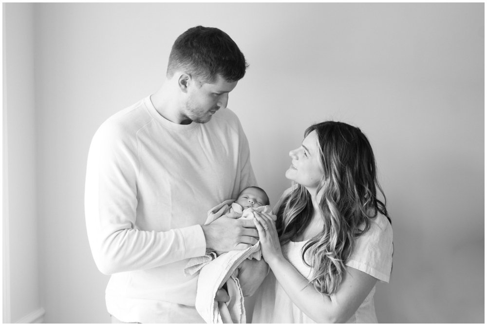 Dad holding newborn while mom looks at dad during newborn session | NKB Photo