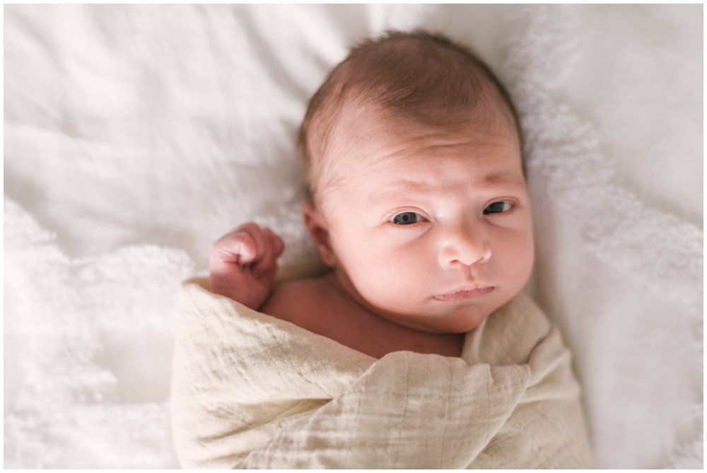 Swaddled newborn baby looking at camera during session | NKB Photo