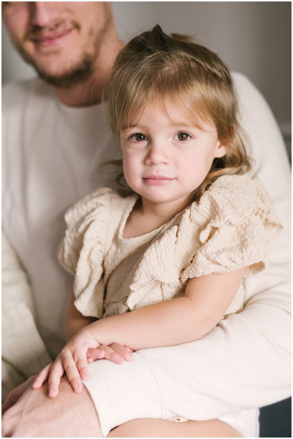 Big sister sitting on dad's lap during newborn session | NKB Photo