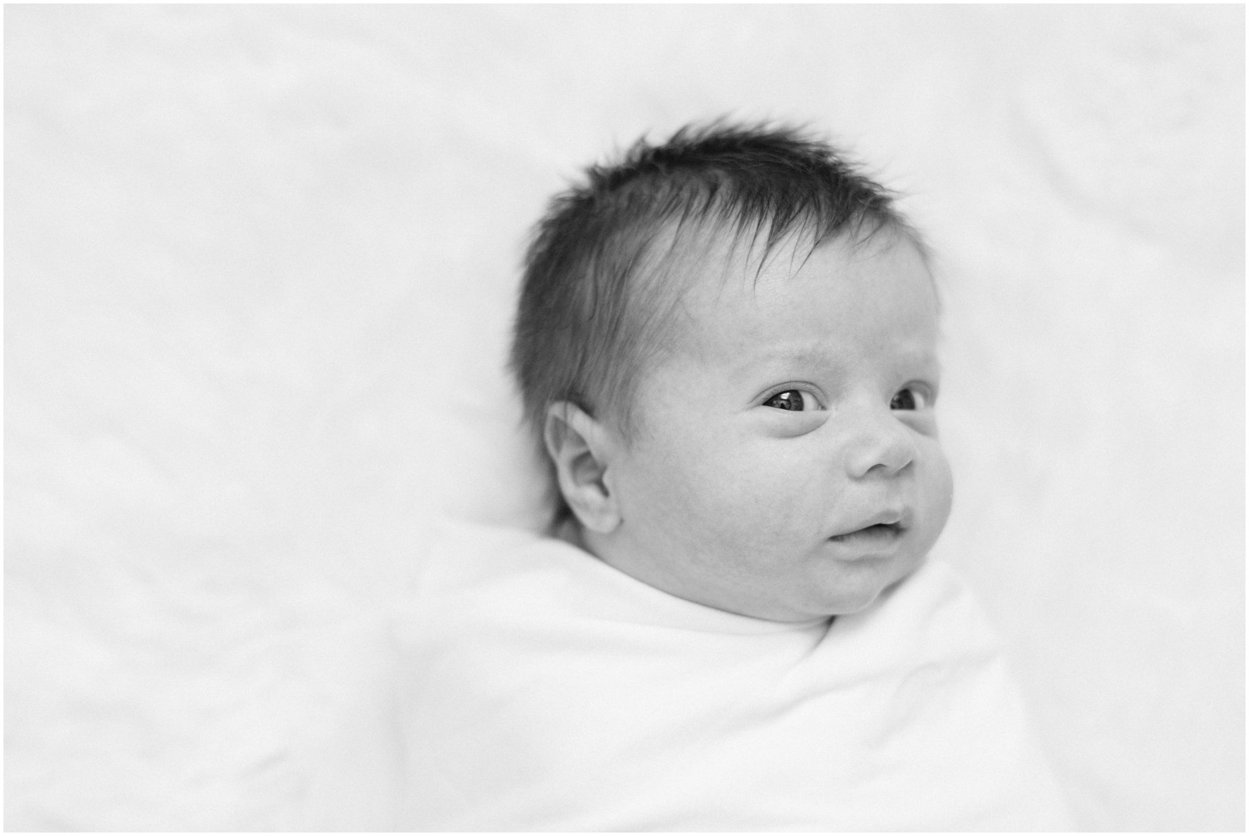 Newborn baby looking at camera while swaddled during Florida milestone photography session | NKB Photo