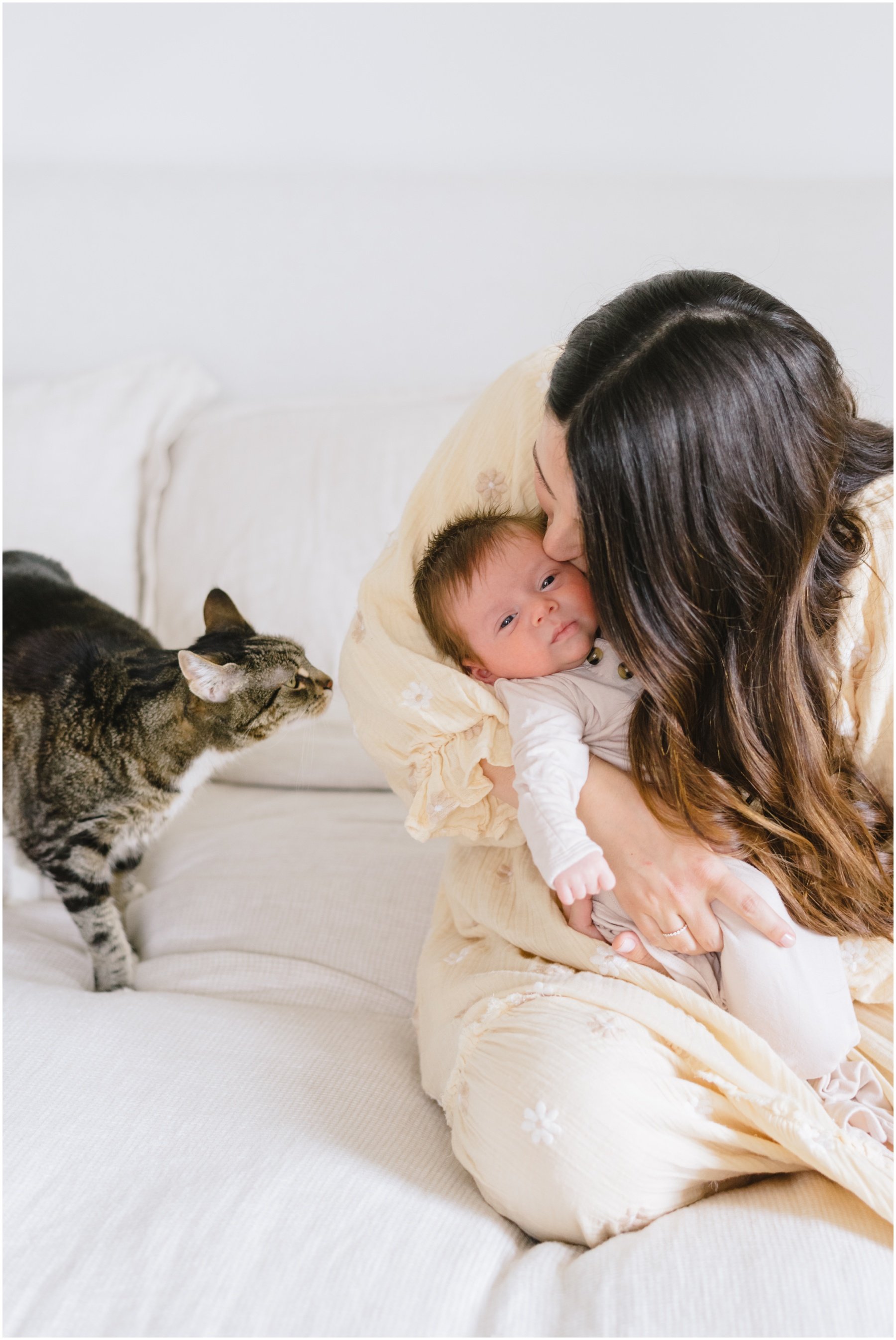 Mom kissing newborn with cat looking at them during  Florida milestone photography session | NKB Photo