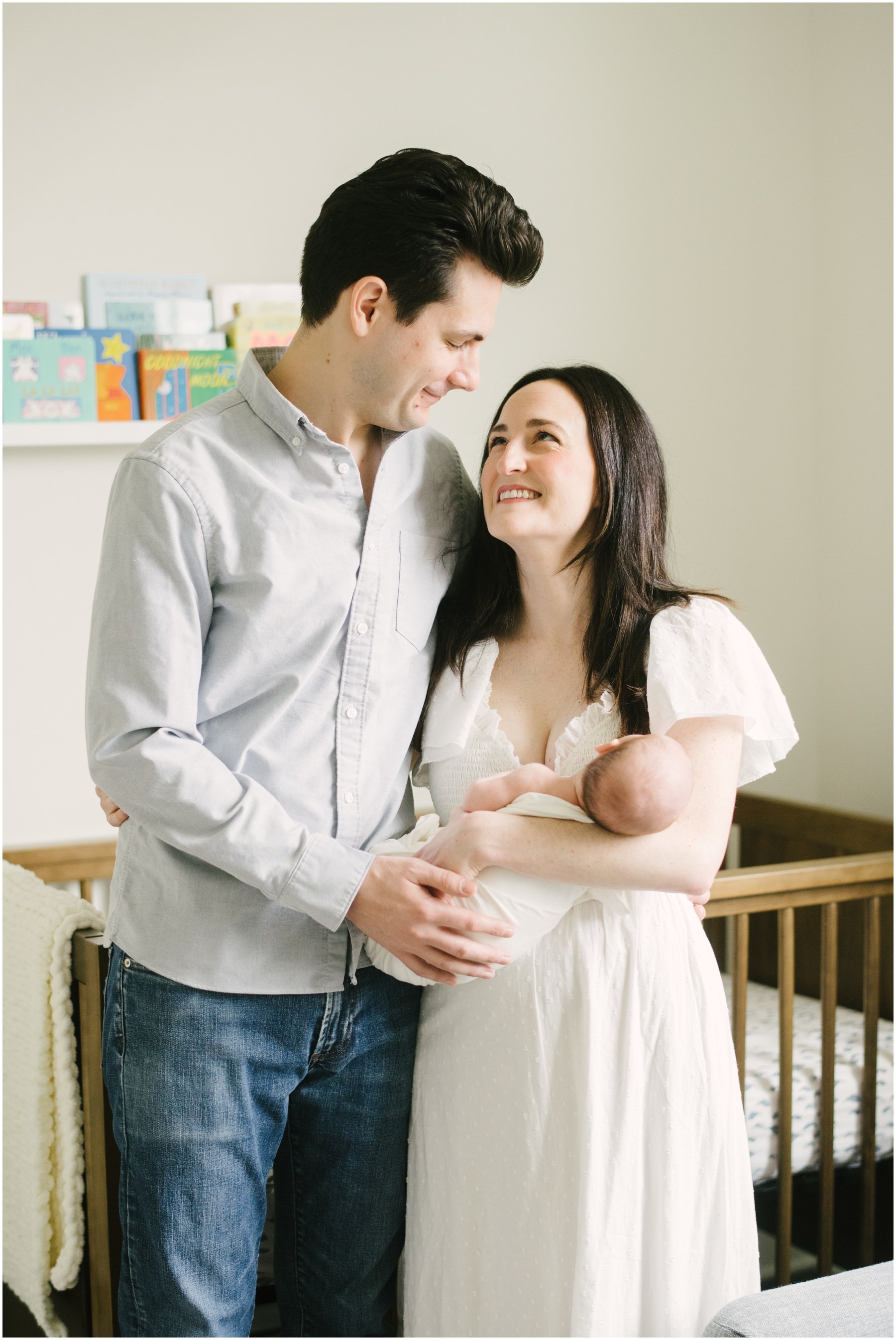 Mom and dad looking at each other in nursery during newborn session  | NKB Photo