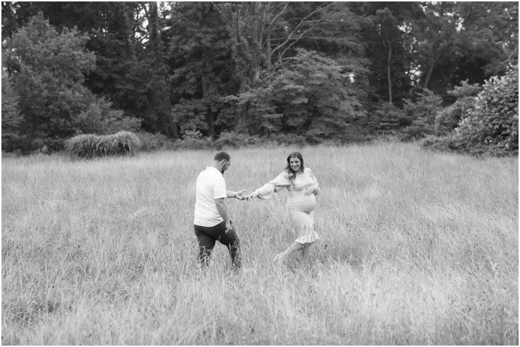 Man and woman walking through field during maternity session | NKB Photo