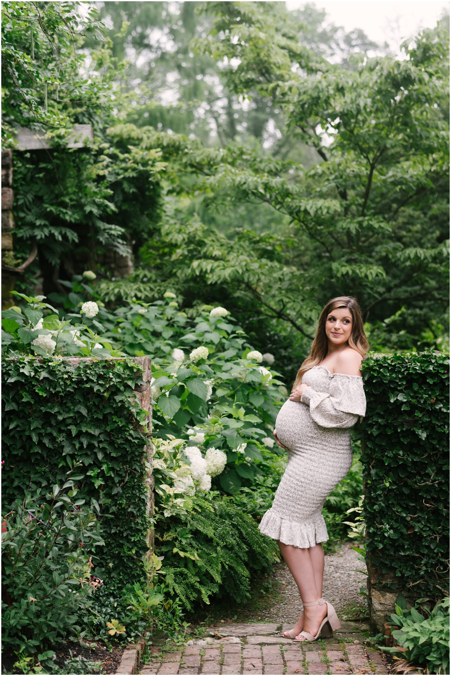 Mom-to-be leaning against garden wall during maternity session | NKB Photo