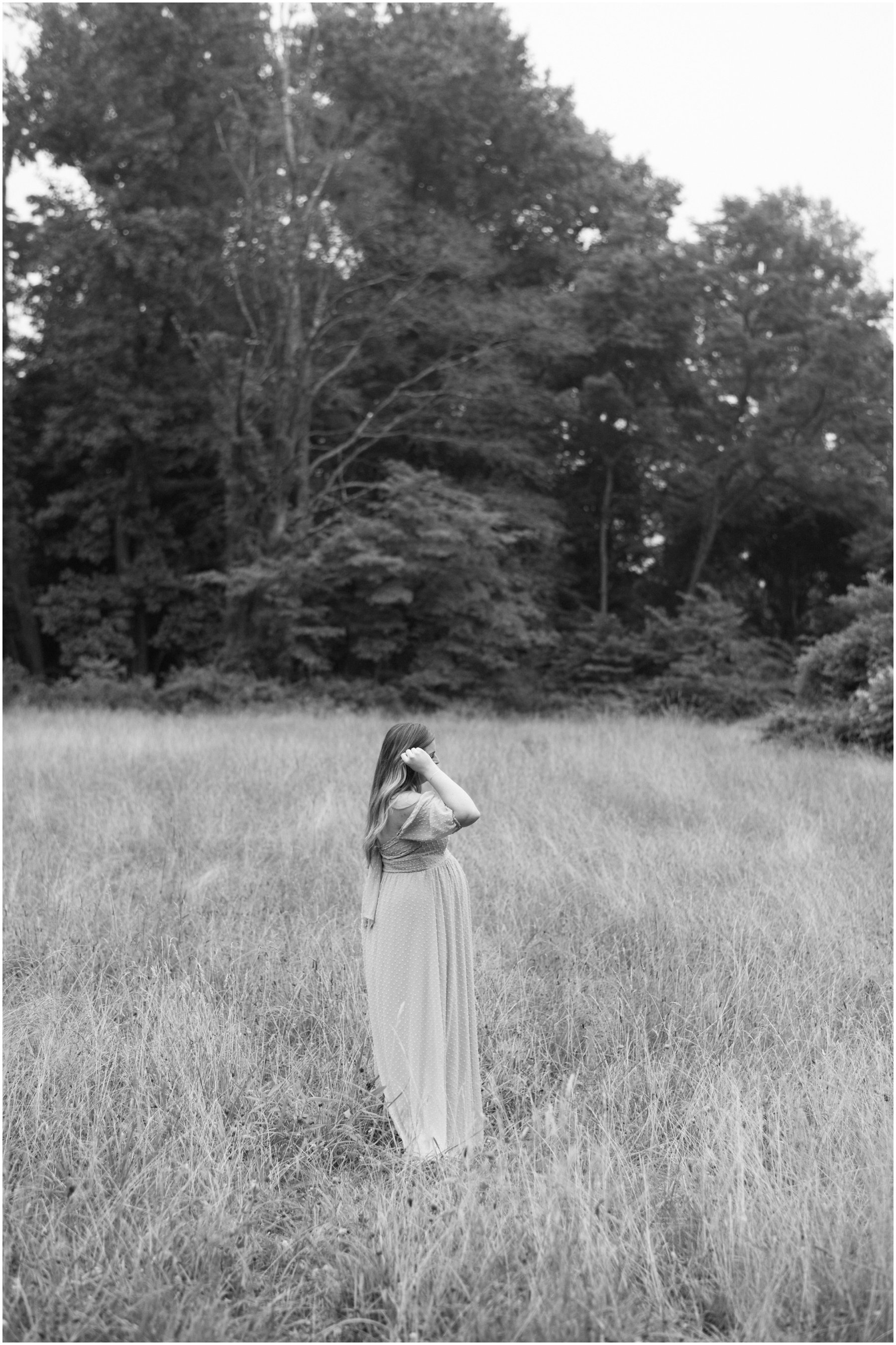 Woman standing in field in flow dress during maternity session | NKB Photo