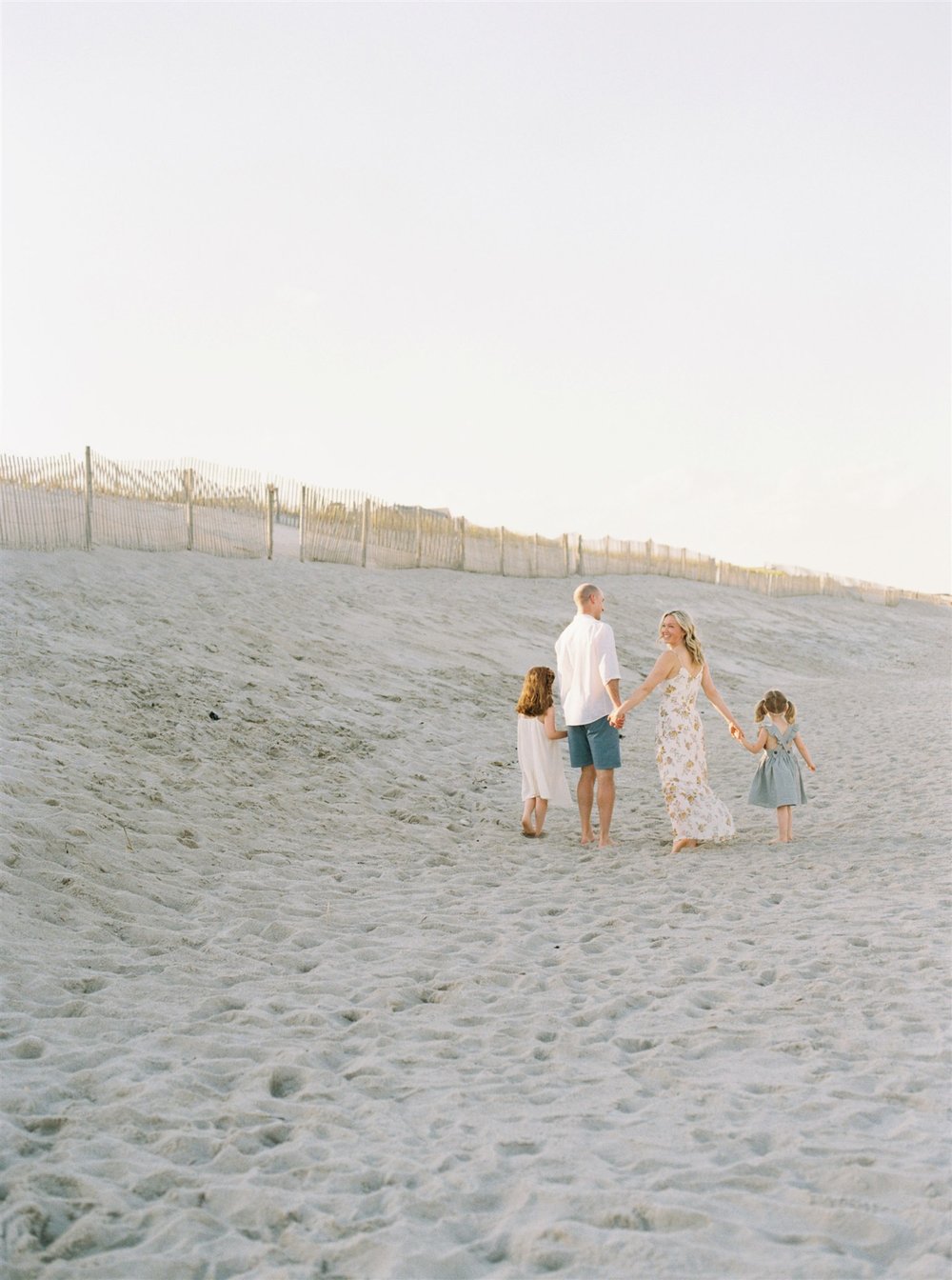 Family walking away from camera holding hands during photo session  | NKB Photo