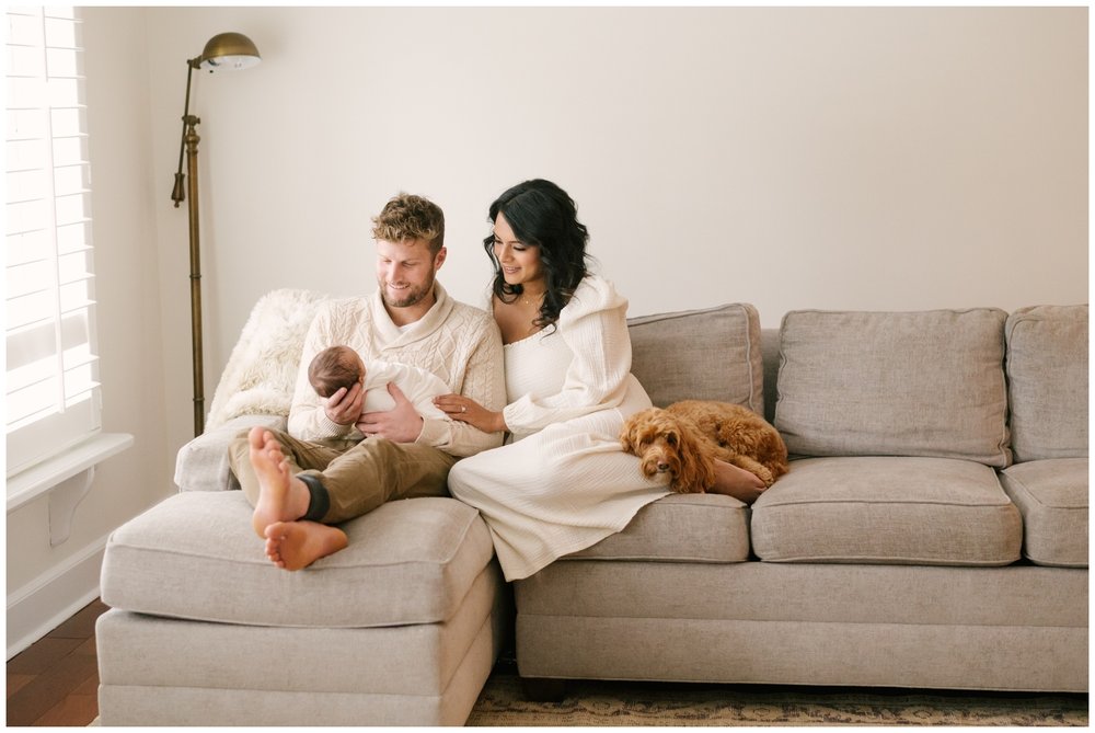 Mom, dad, newborn, and dog sitting on couch during newborn session | NKB Photo
