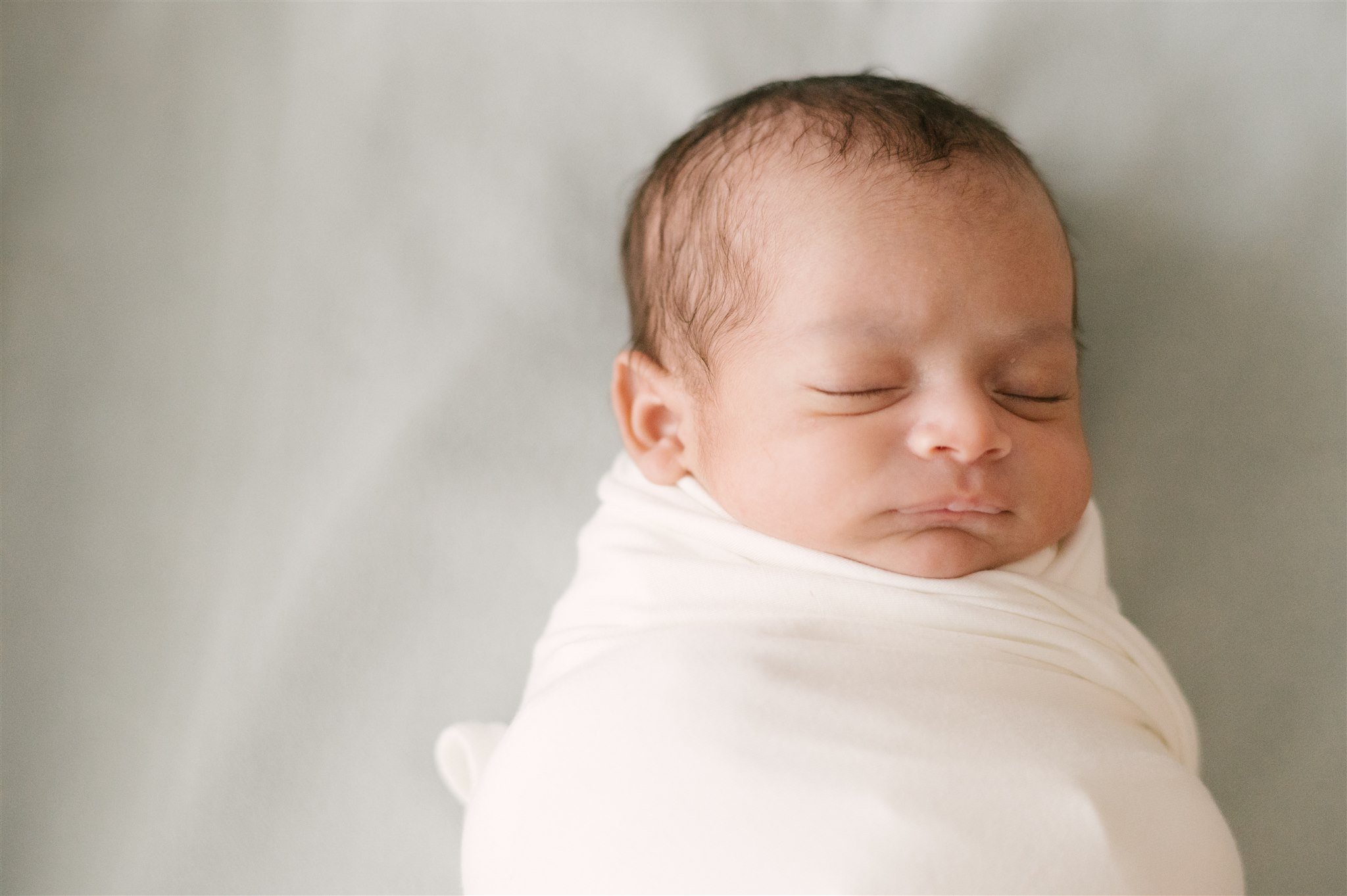 Swaddled newborn sleeping during session with West Palm Beach newborn photographer