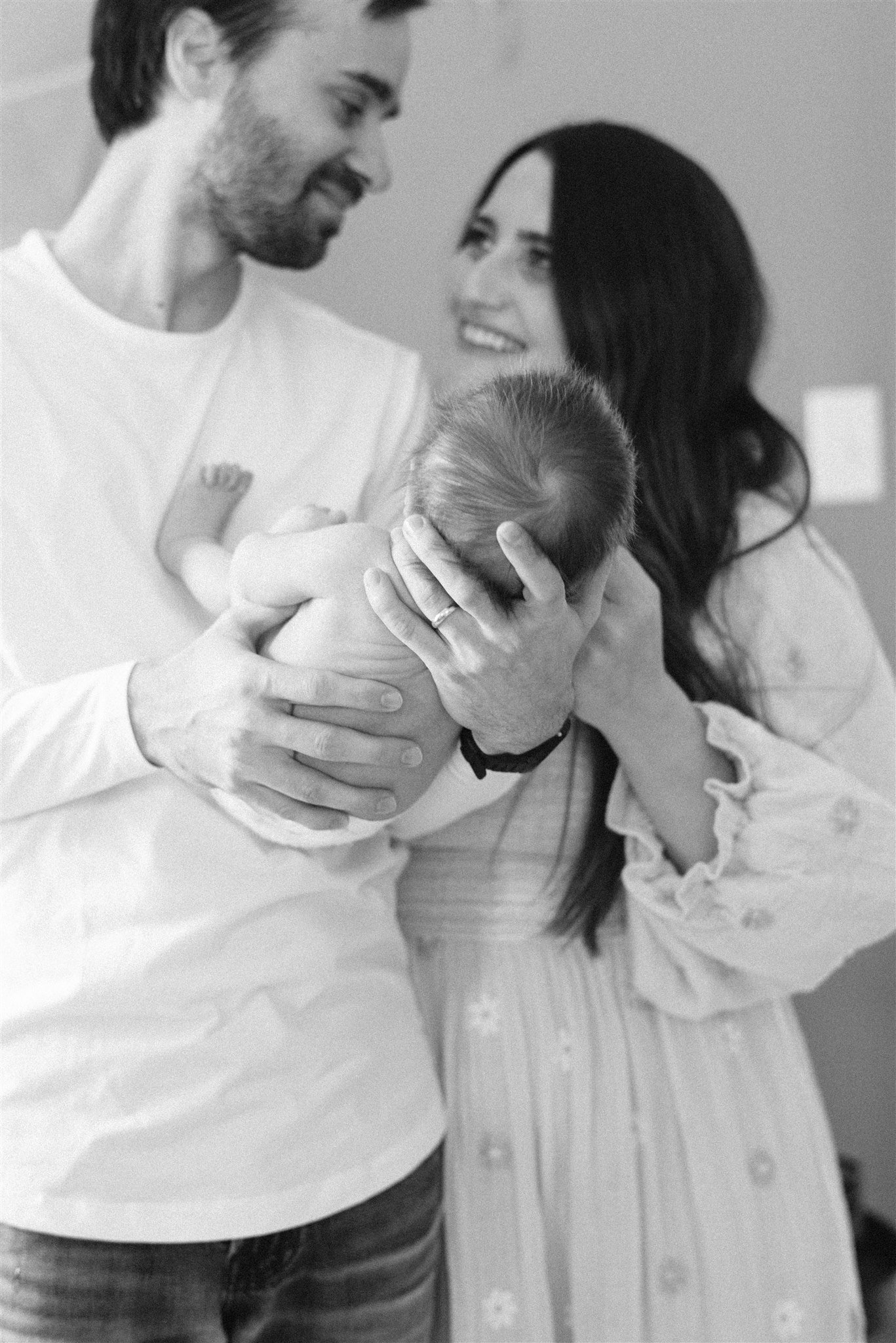 Mom and dad looking at each other while holding newborn