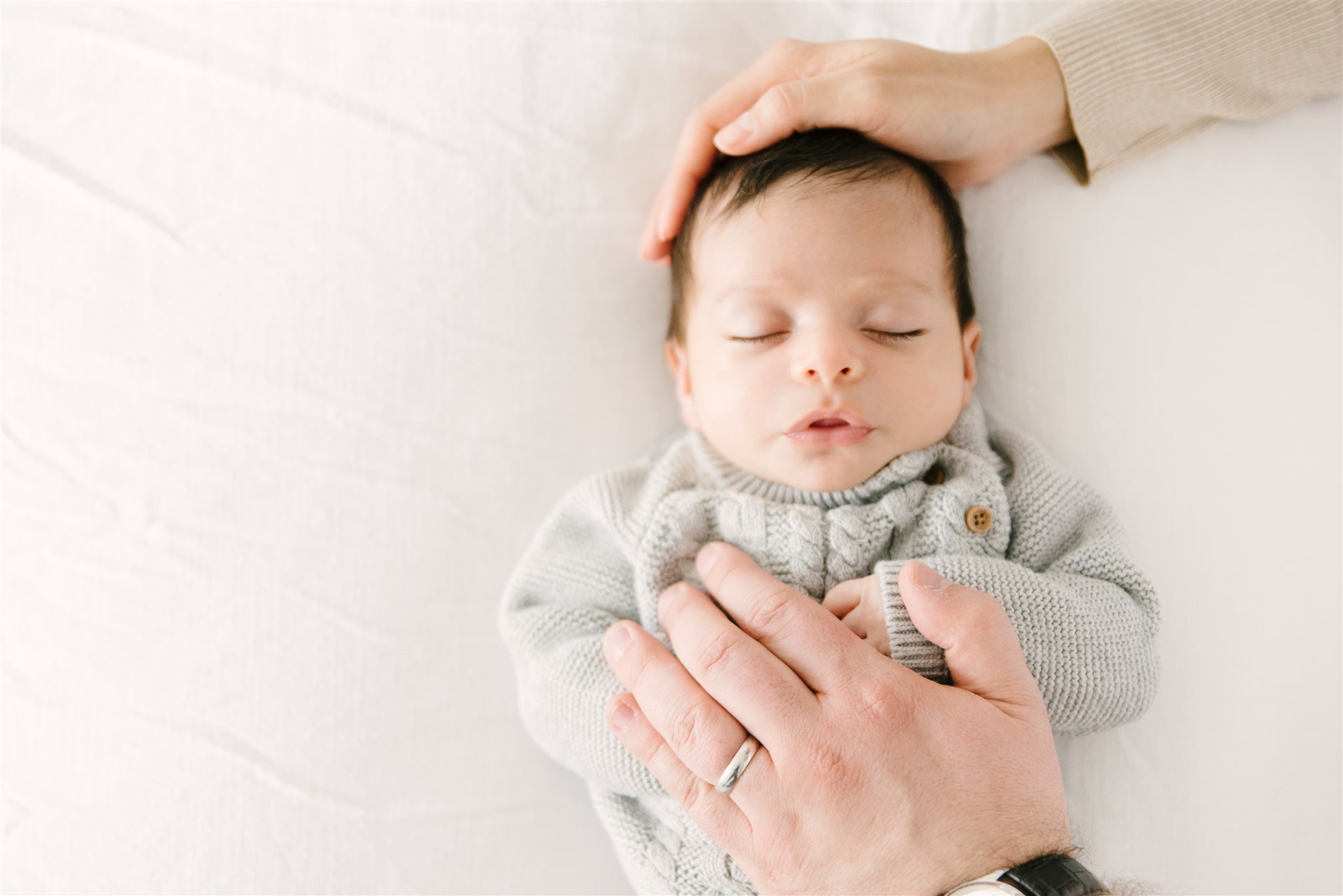 Parents hands on sleeping newborn during newborn session with Boca Raton photographer