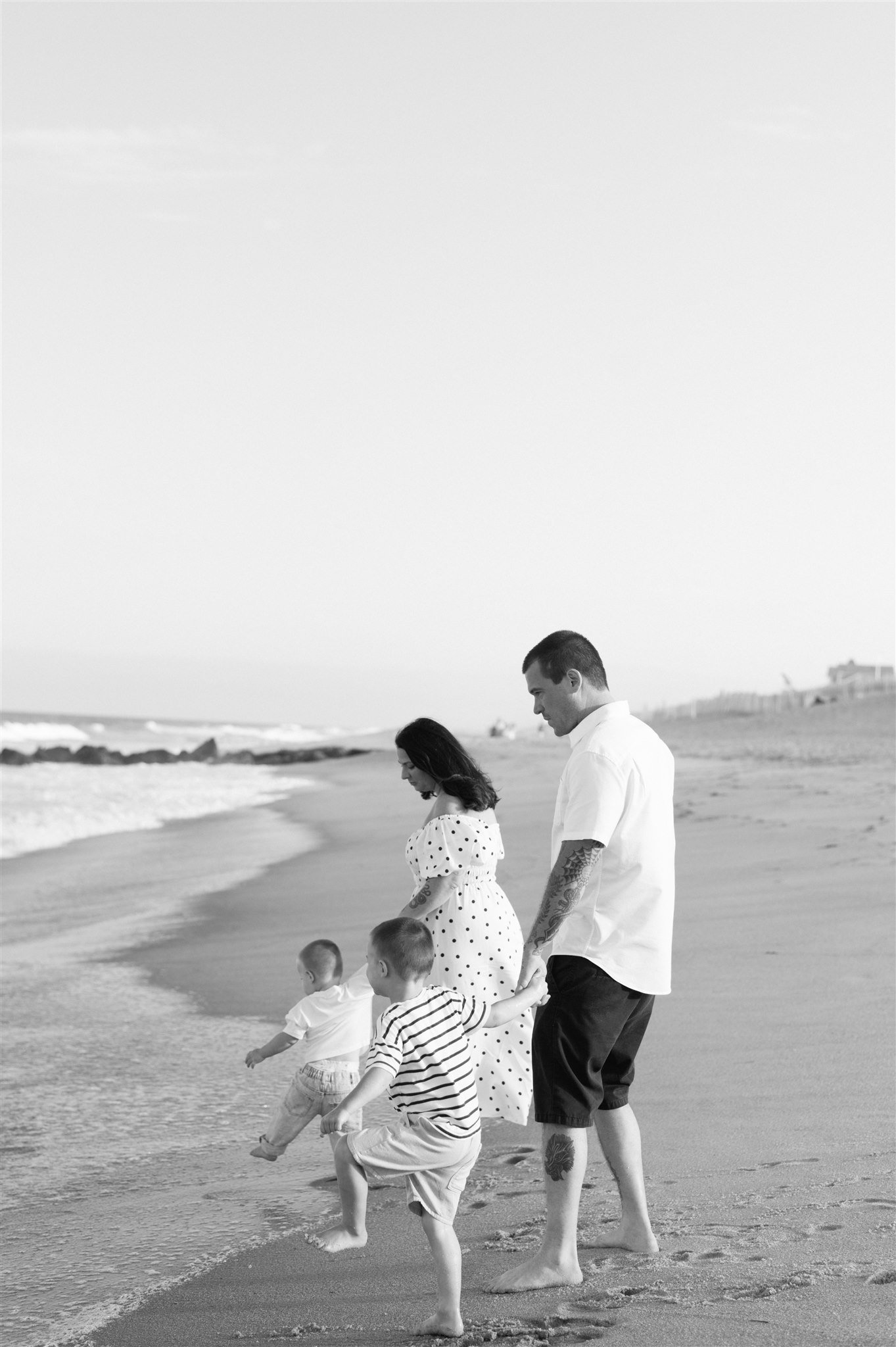 Family holding hands and walking on beach during session with Parkland family photographer 